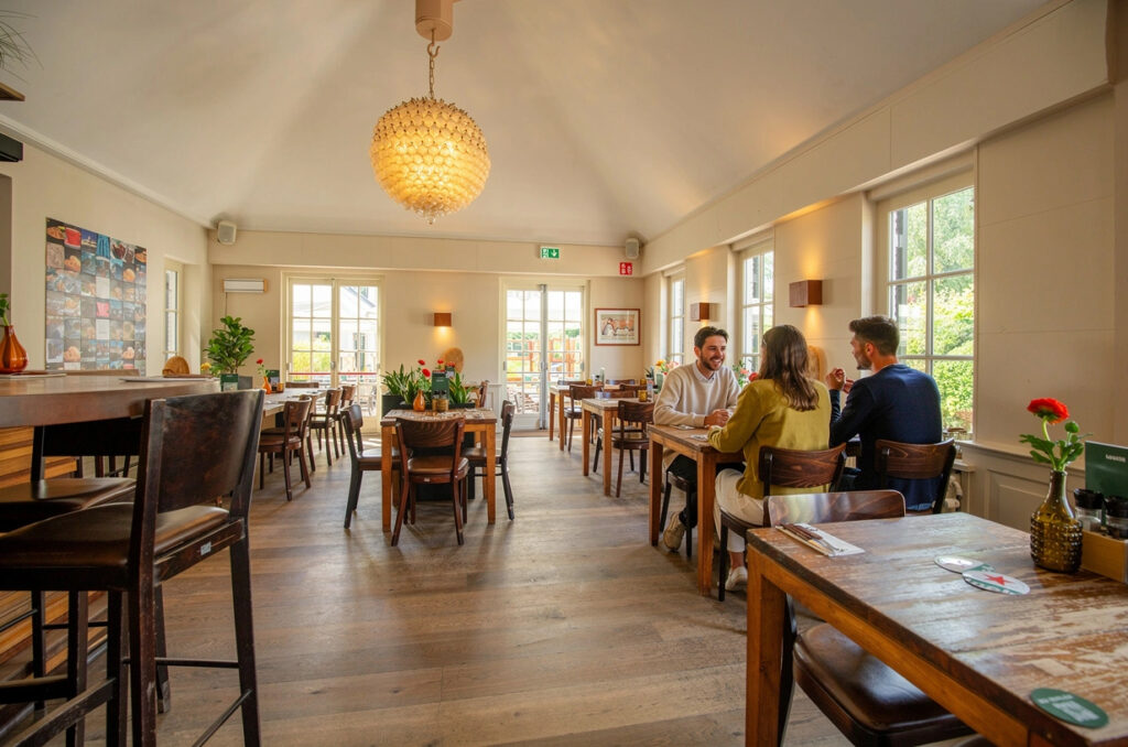 Gasten aan tafel in de lichte eetzaal van Loetje aan de Amstel.