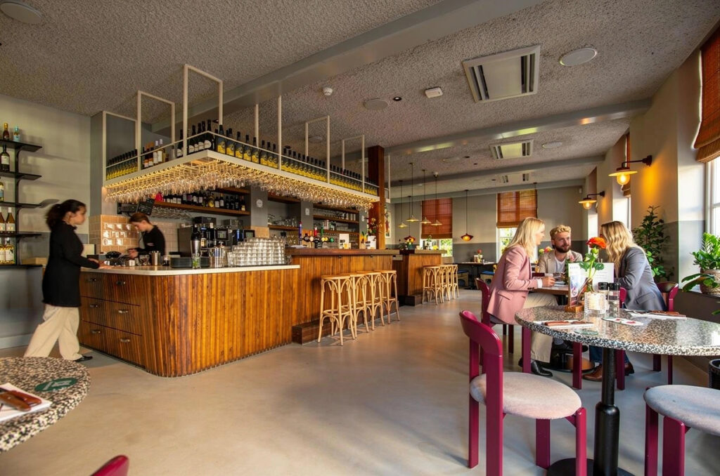 Interieur van Loetje Breukelen met houten bar en gasten aan tafel.