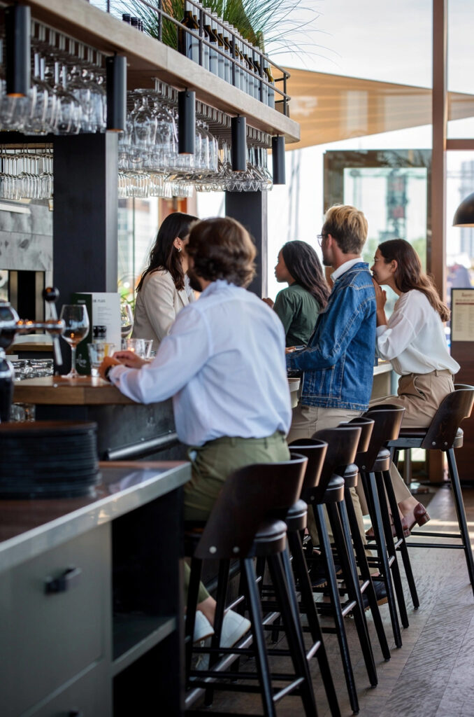 Gasten zitten samen aan de bar van Loetje aan ’t IJ.
