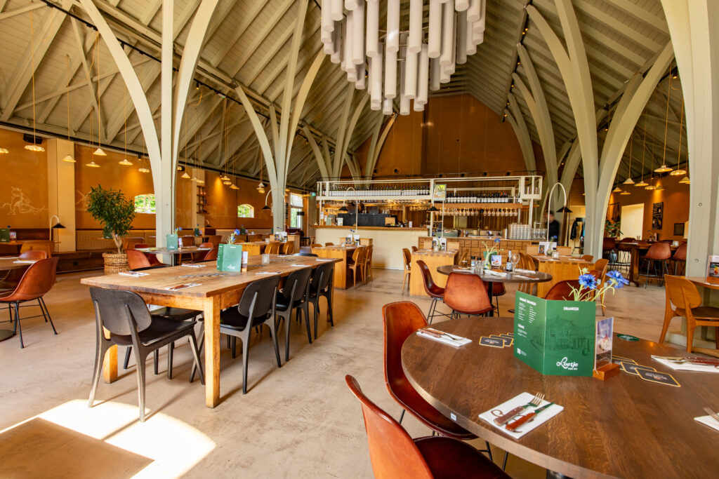 Restaurantzaal van Loetje Houten met karakteristieke hoge spanten en de bar op de achtergrond.