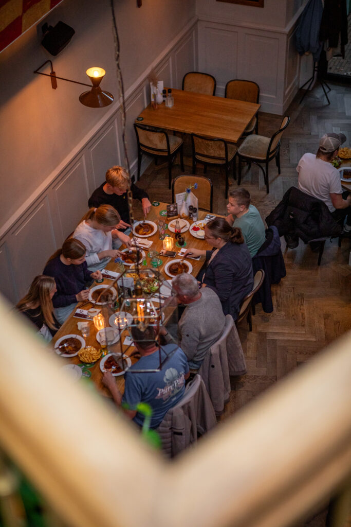 Groot gezelschap geniet samen van een diner aan een lange tafel bij Loetje Leeuwarden.