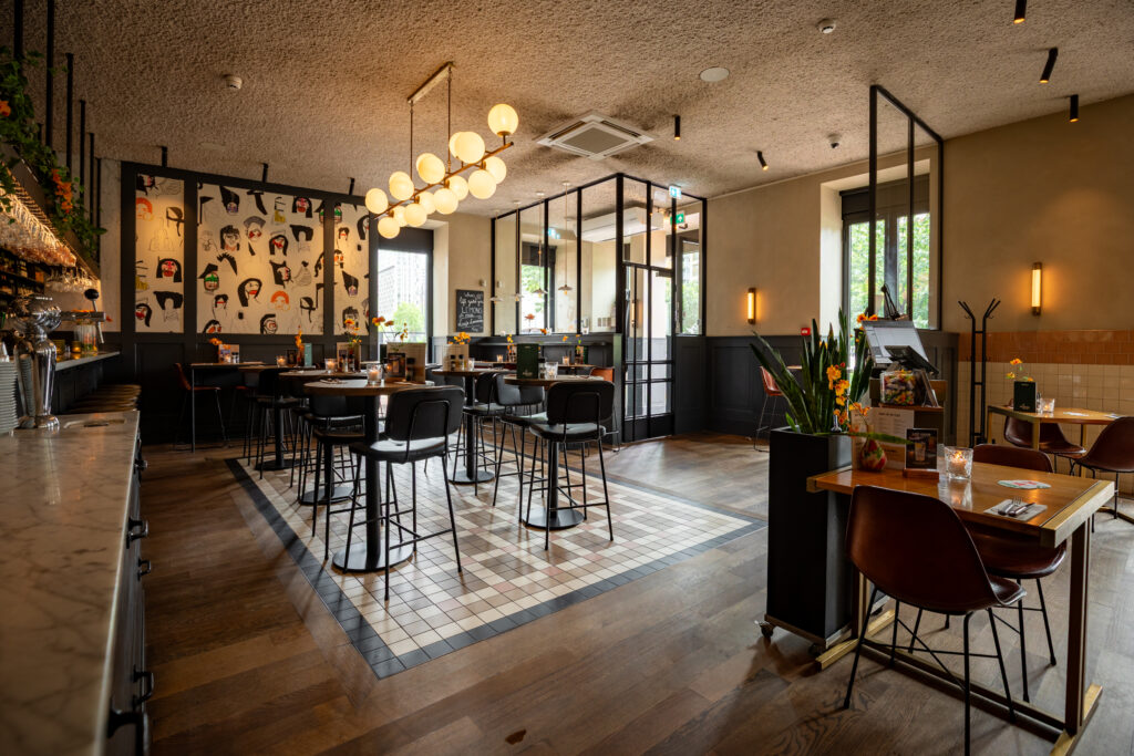 Restaurantgedeelte van Loetje Rotterdam Blaak met hoge tafels en karakteristieke wanddecoratie.