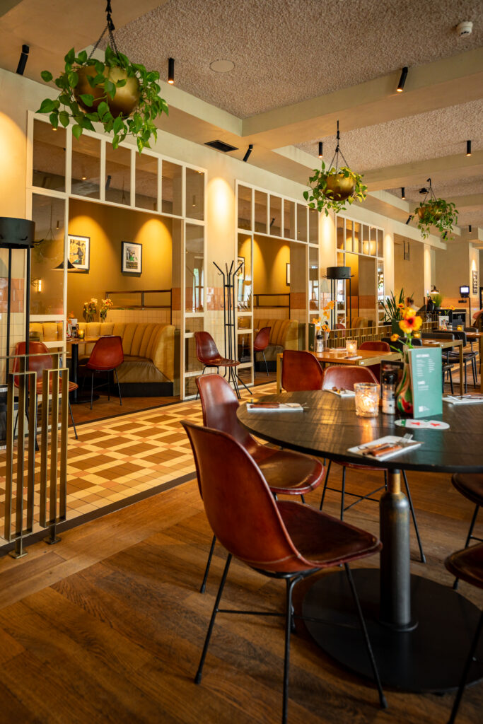 Sfeervol interieur van Loetje Rotterdam Blaak met zitbanken, planten en gedekte tafels.