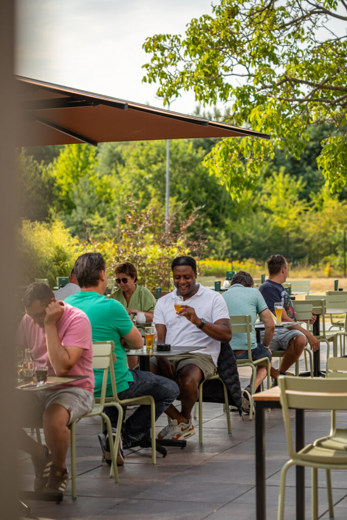 Gasten op het zonnige terras van Loetje Vught, omringd door groen.