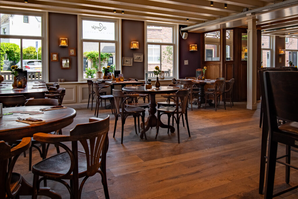 Restaurantgedeelte van Loetje aan de Amstel met houten tafels en grote ramen.