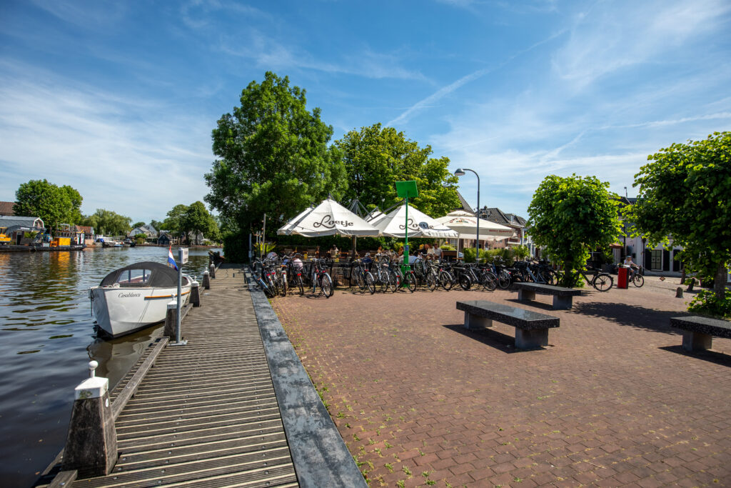 Terras van Loetje aan de Amstel aan het water met aangemeerde boot en fietsen.