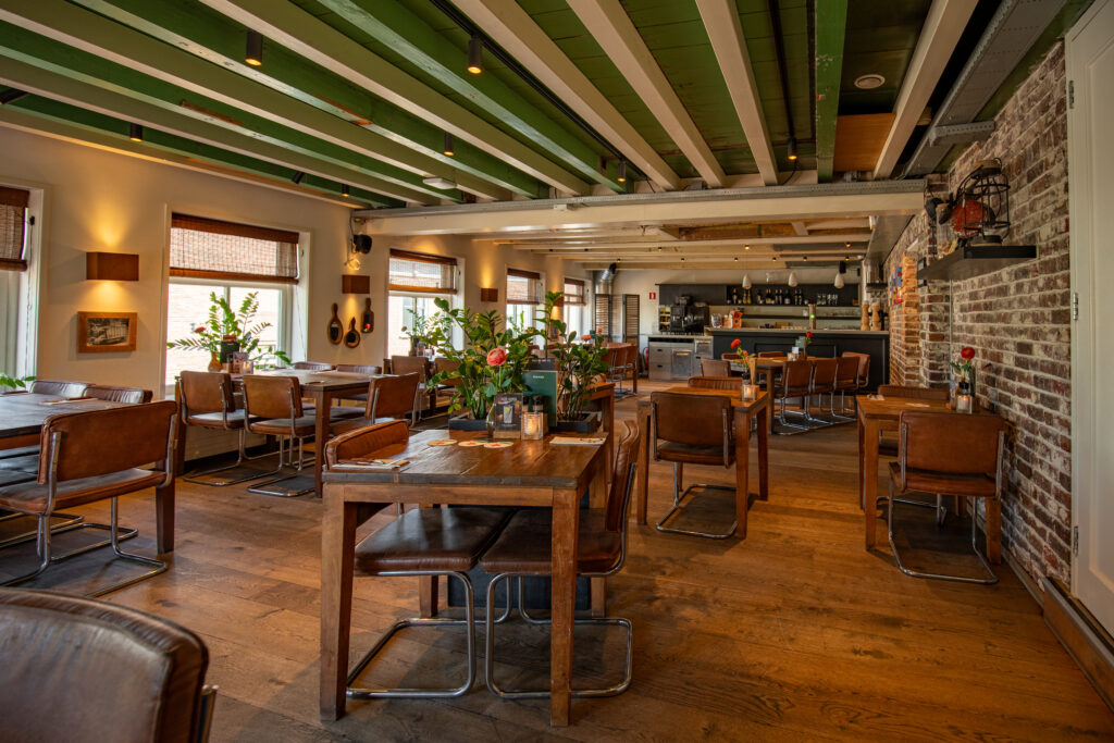 Sfeervol interieur van Loetje aan de Amstel met houten tafels, leren stoelen en de bar.