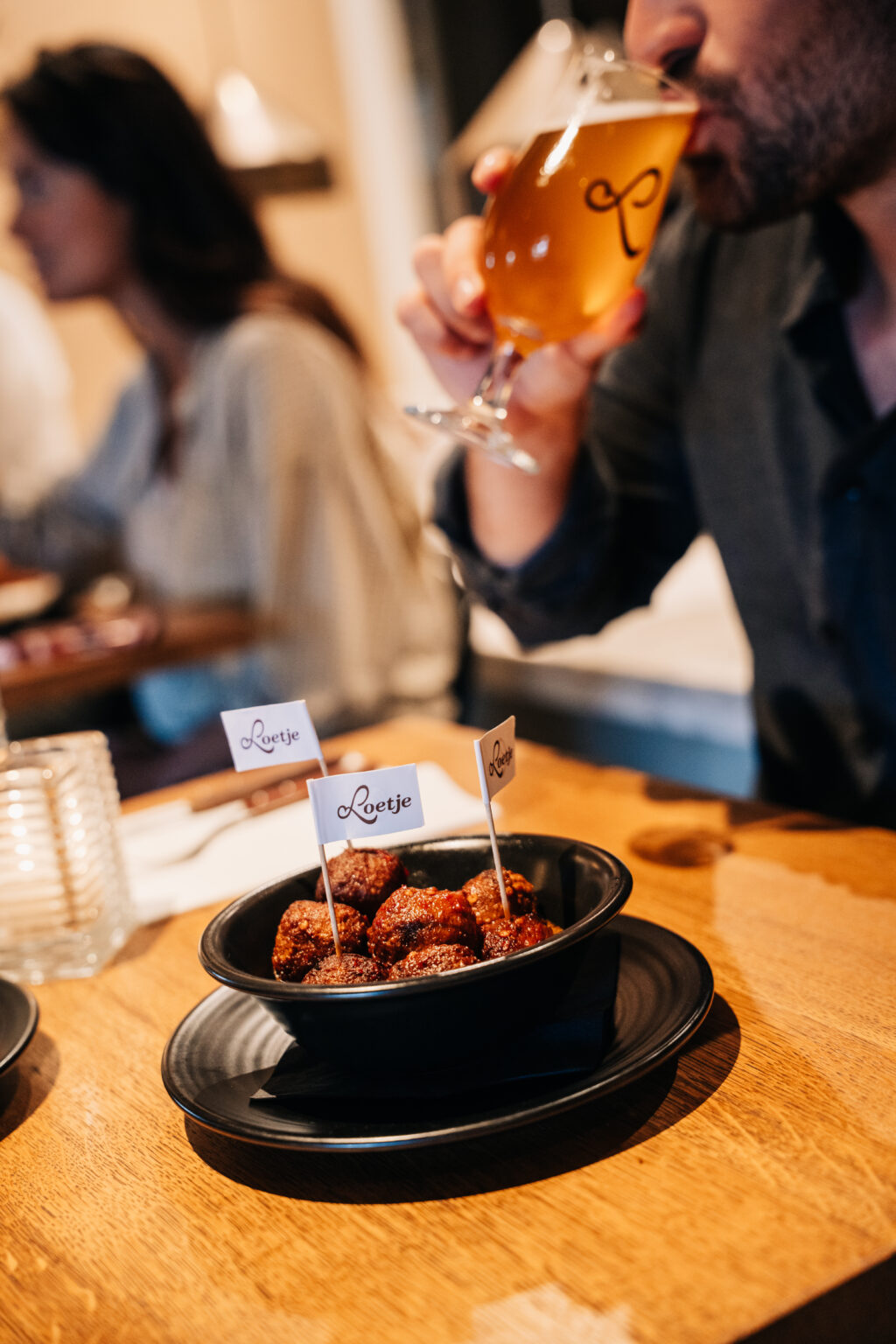 Man drinkt een biertje bij Loetje met een schaal bitterballen op tafel.