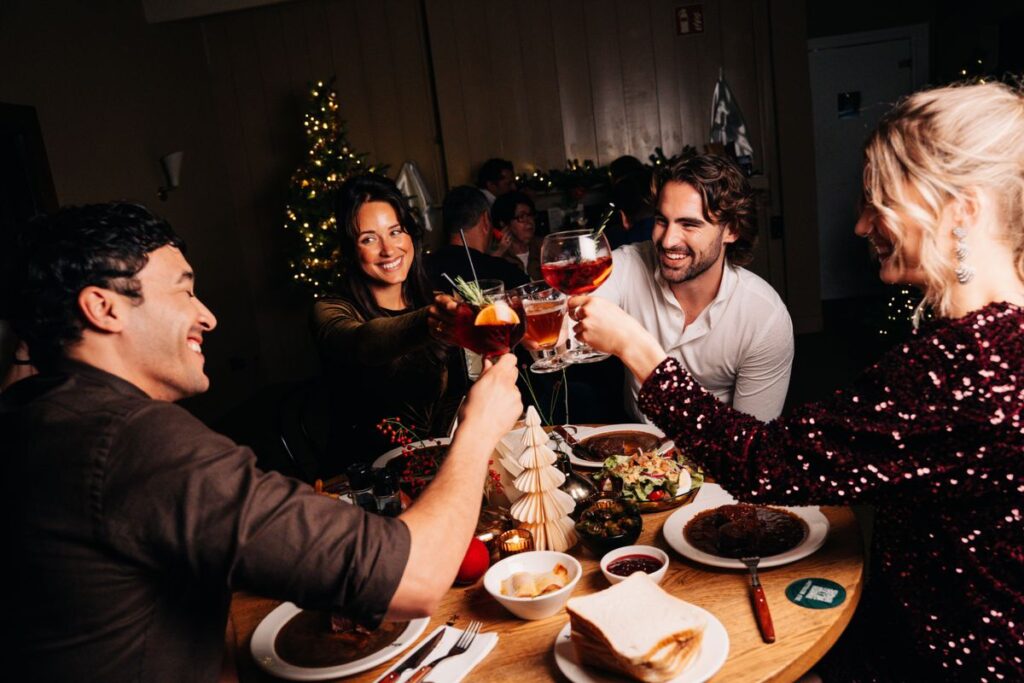 Vier gasten proosten tijdens een feestelijk kerstdiner bij Loetje.