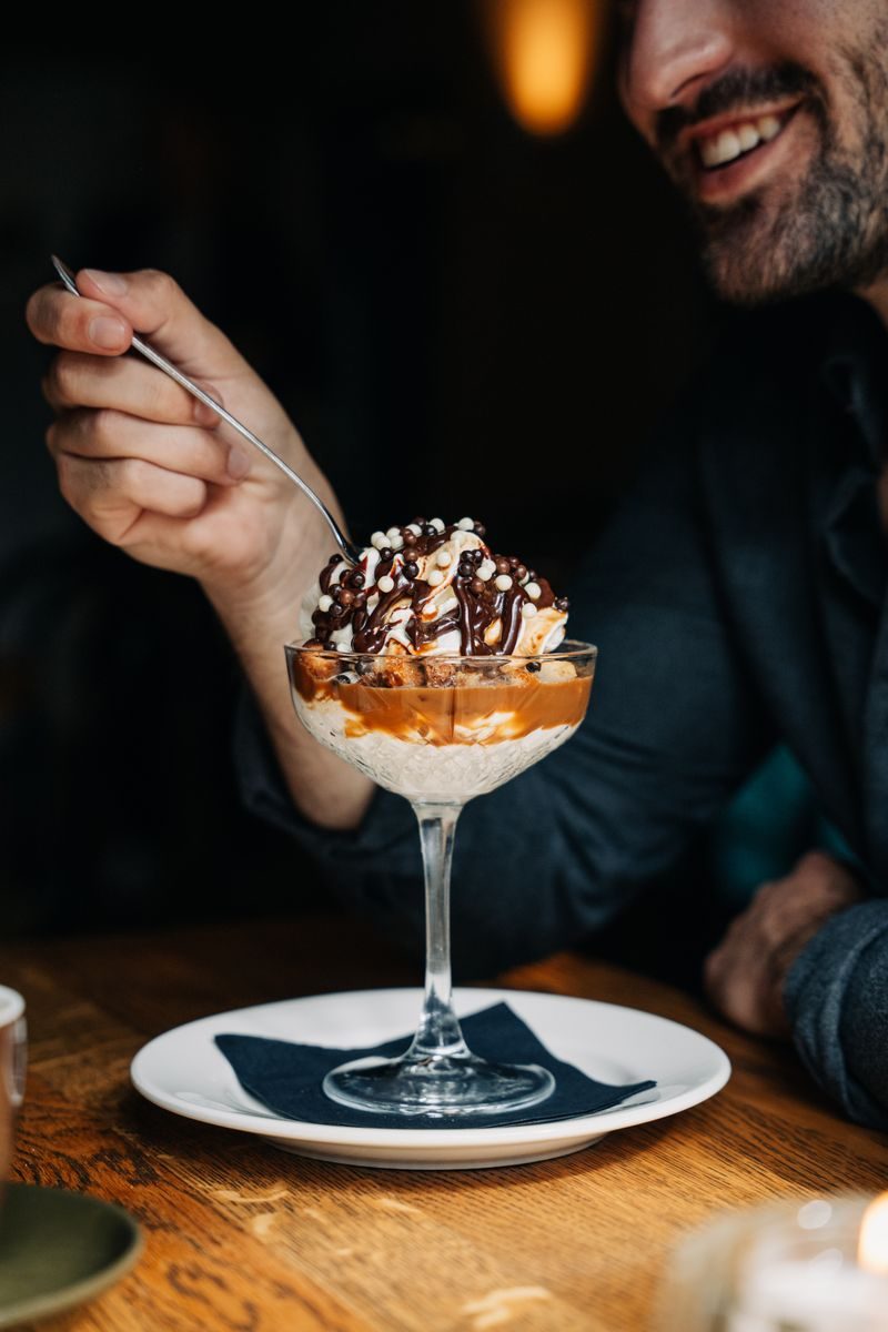 Bananen coupe met vanille-ijs, banaan, sticky toffee saus, chocoladesaus en muffin crunch.